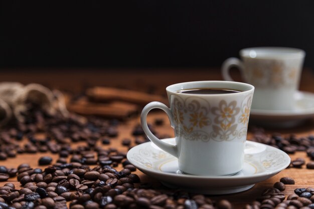 Taza en platillo cerca de granos de café