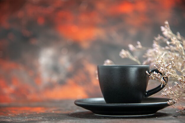 Taza y platillo negros de vista frontal en la mesa de color rojo oscuro con espacio libre