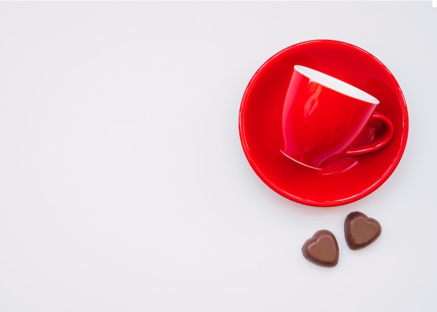 Taza en el plato cerca de dulces de chocolate dulces