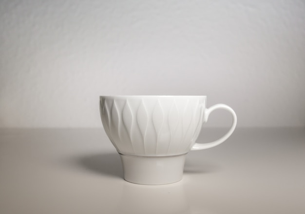 una taza de porcelana blanca sobre un fondo blanco