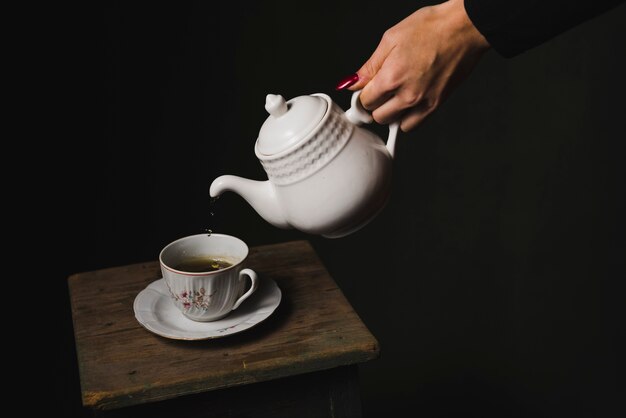 Taza de relleno de la mano de la cosecha con té