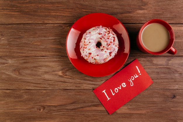 Taza roja con donut y nota de amor.