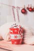 Foto gratuita taza roja con malvaviscos y bastones de caramelo y bolas de navidad