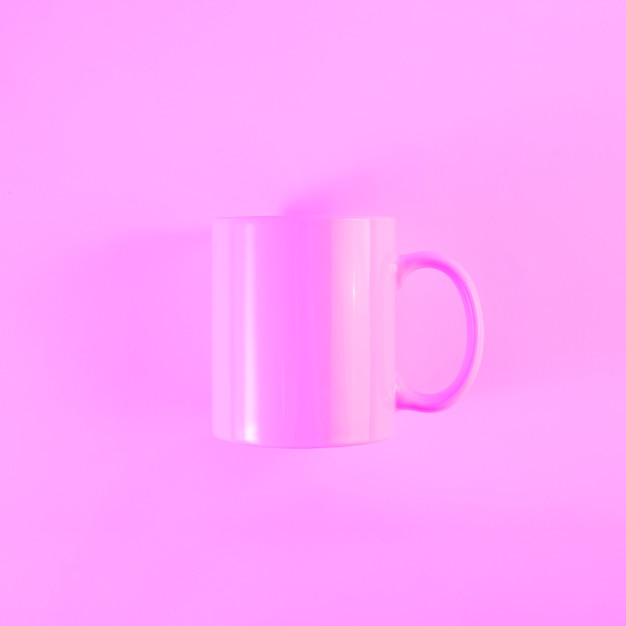 Foto gratuita taza rosa pintada con asa contra fondo coloreado.