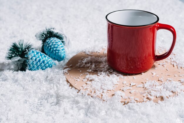 Taza en el stand cerca de los juguetes de Navidad entre la nieve.