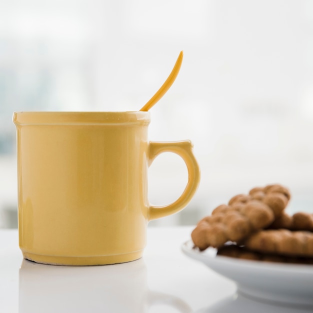 Taza de té amarilla con galletas