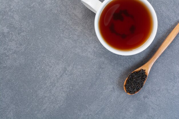 Una taza de té aromático con una cuchara de madera de infusión.