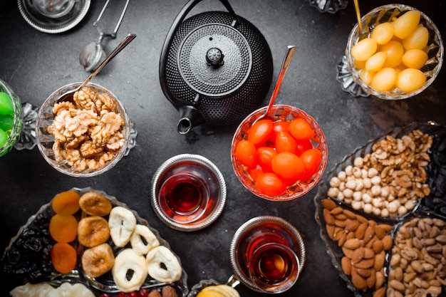 Taza de té aromático y jarrones con mermelada, frutas secas