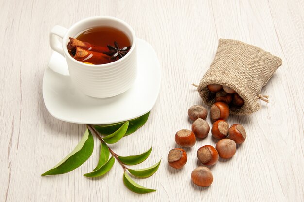 Taza de té con avellanas frescas sobre blanco