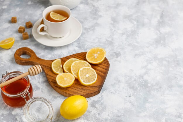 Una taza de té, azúcar morena, miel y limón sobre hormigón. Vista superior, espacio de copia