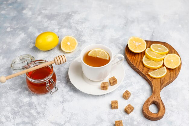Una taza de té, azúcar morena, miel y limón sobre hormigón. Vista superior, espacio de copia