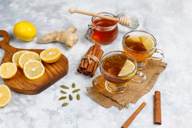 Una taza de té, azúcar morena, miel y limón sobre hormigón. Vista superior, espacio de copia