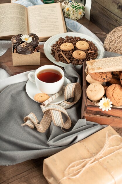 Una taza de té, bombones de chocolate y una bandeja de galletas.