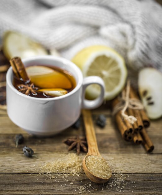 Taza de té caliente con palitos de canela y limón