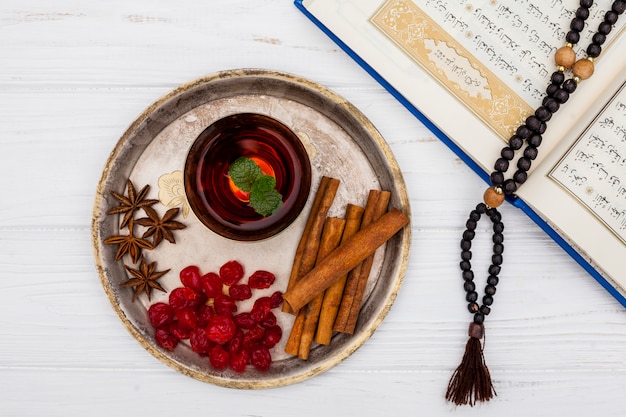 Foto gratuita taza de té con canela y corán sobre mesa