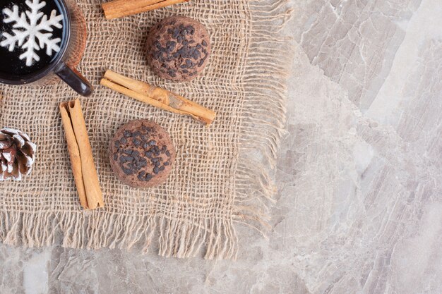 Taza de té, canela y galletas en mármol.