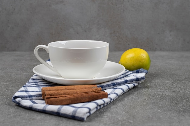 Foto gratuita taza de té, canela y limón sobre superficie de mármol