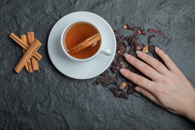 Una taza de té con canela en rama e infusión.