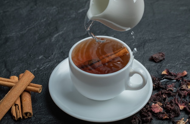 Una taza de té con canela en rama e infusión.