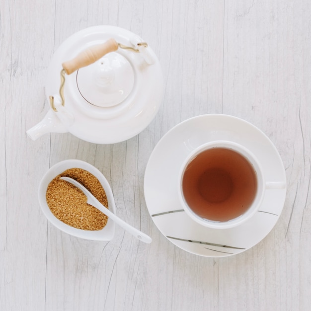 Taza de té cerca de azúcar y tetera