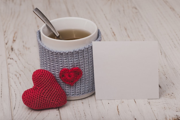 Taza de té con un corazón con un papel blanco y un corazón