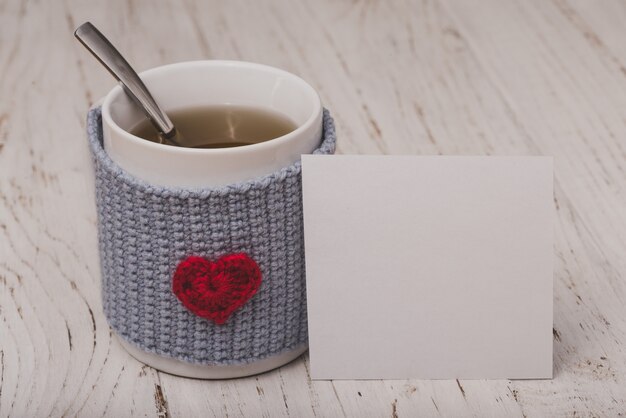 Taza de té con un corazón con un papel blanco