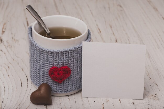 Taza de té con un corazón con un papel blanco