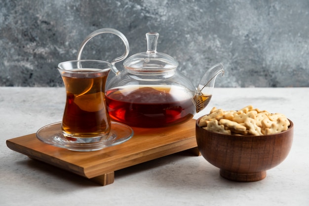 Una taza de té con cuenco de madera lleno de galletas.