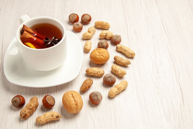 taza de té con diferentes frutos secos en blanco