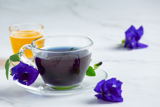 Taza de té de flor de guisante de mariposa con miel en la mesa