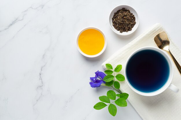 Taza de té de flor de guisante de mariposa con miel en la mesa