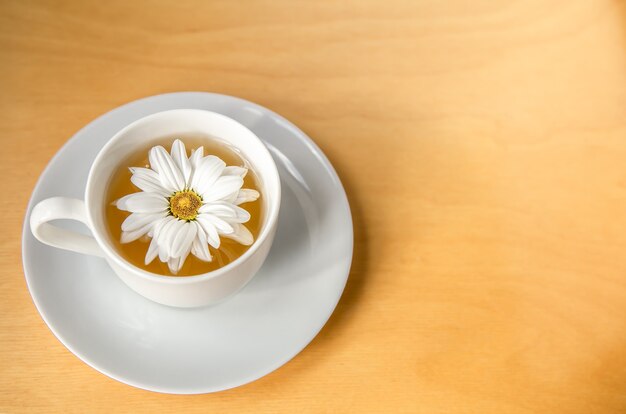 Taza de té con flor de manzanilla en un espacio de copia de fondo de madera