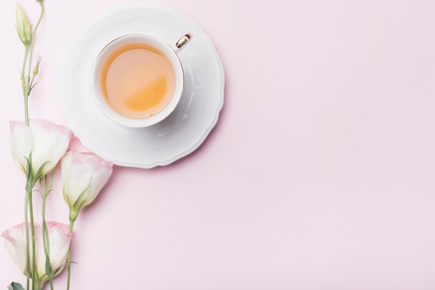 Taza de té con flores de eustoma sobre fondo rosa