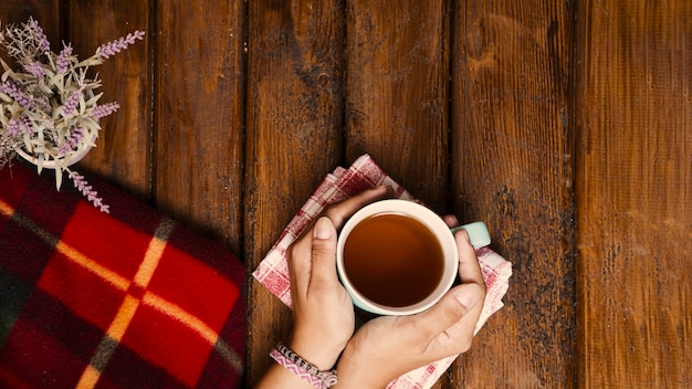 Taza de té, flores y manta de invierno en madera vieja