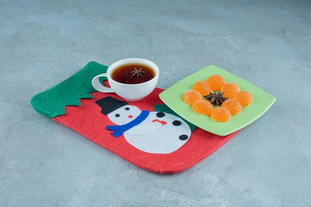 Taza de té y fuente de mermelada en un calcetín de Navidad en mármol.