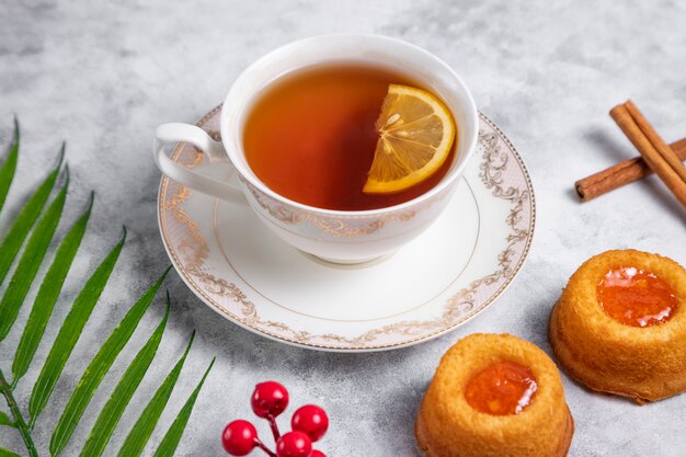 Una taza de té con galleta de huella digital de mermelada de albaricoque casera.