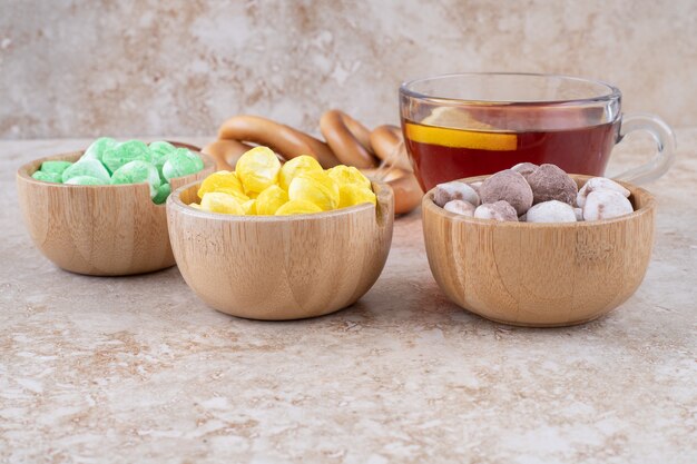 Taza de té, galletas y cuencos de dulces en la superficie de mármol