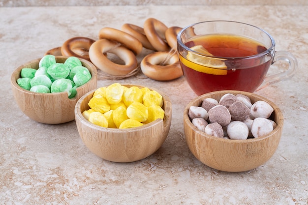 Taza de té, galletas y cuencos de dulces en la superficie de mármol