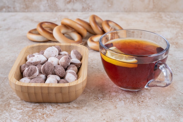 Taza de té, galletas y tazón de dulces en la superficie de mármol