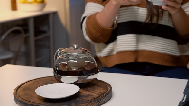 Taza de té y hervidor de agua sentado en la mesa de la cocina blanca