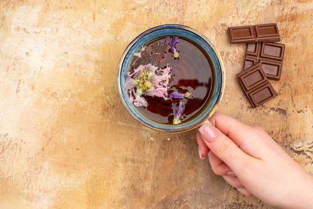 Una taza de té de hierbas caliente y barras de chocolate en la tabla de colores mezclados