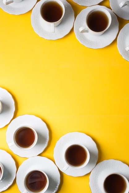 Taza de té de hierbas y platillos en la esquina del fondo amarillo