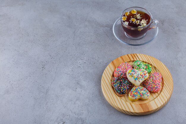 Taza de té de hierbas con plato de galletas dulces sobre fondo de piedra.