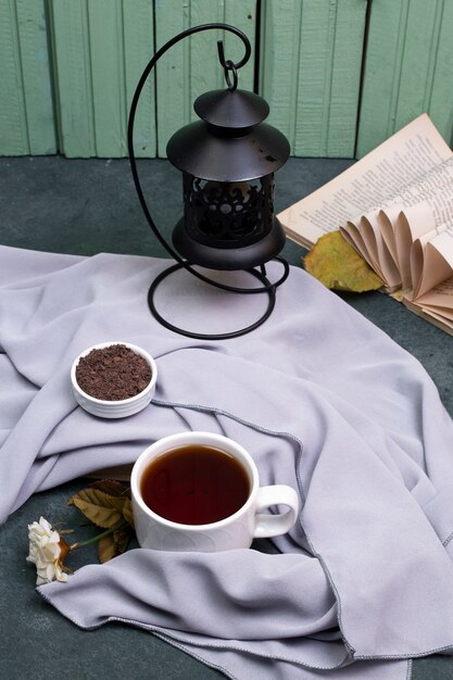 Una taza de té y hierbas en un plato sobre la mesa, un libro alrededor