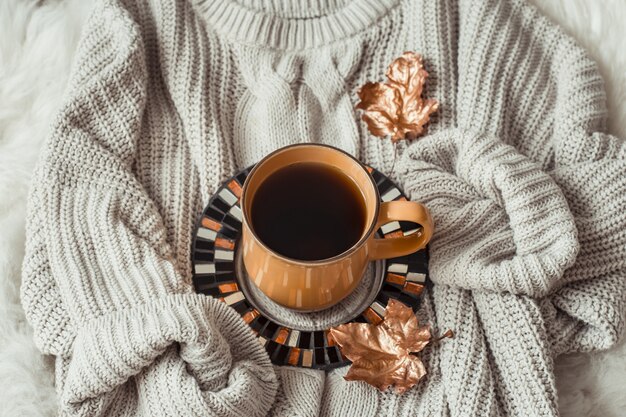 Taza de té con hojas de otoño y suéter