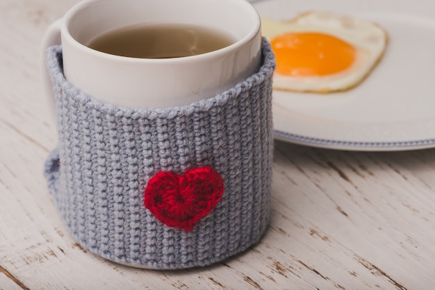 Taza de té con un huevo frito detrás