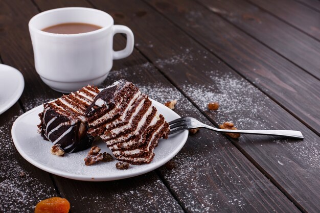 Taza de té con leche y dos platos con tarta de queso y chocolate