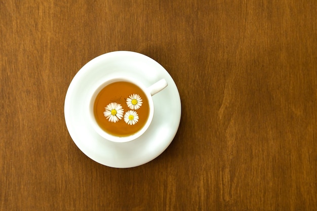 Taza de té de manzanilla sobre fondo de madera endecha plana