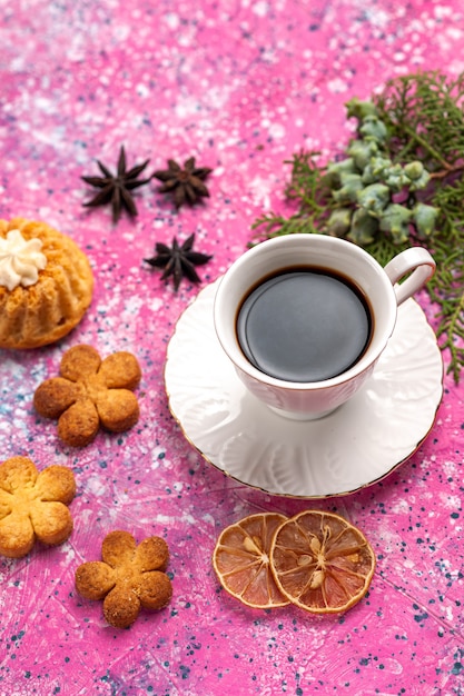 Taza de té de media vista superior con pastelito y galletas en el escritorio de color rosa claro.