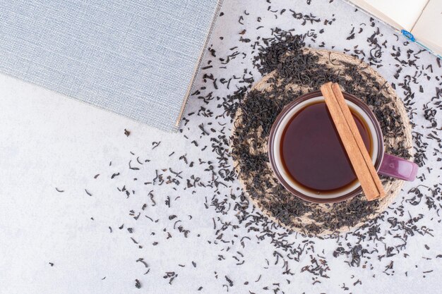 Taza de té negro con canela en rama y té seco